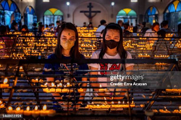 Filipino Catholics with ash on their foreheads light candles as they observe Ash Wednesday at Baclaran Church on February 22, 2023 in Paranaque,...