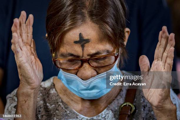 Woman with ash on her forehead prays in observance of Ash Wednesday at Baclaran Church on February 22, 2023 in Paranaque, Metro Manila, Philippines....