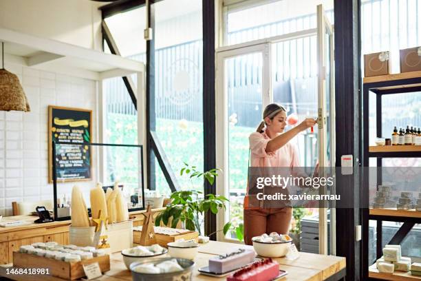 young business owner unlocking front door of retail shop - unlocking stock pictures, royalty-free photos & images