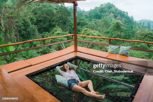 frau liegt in hängematte auf der terrasse und schaut auf den dschungel - thailand strand stock-fotos und bilder