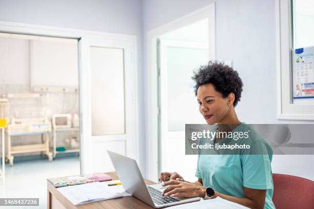 professional smiling black female head nurse or doctor uses medical computer. - pleased face laptop stock pictures, royalty-free photos & images