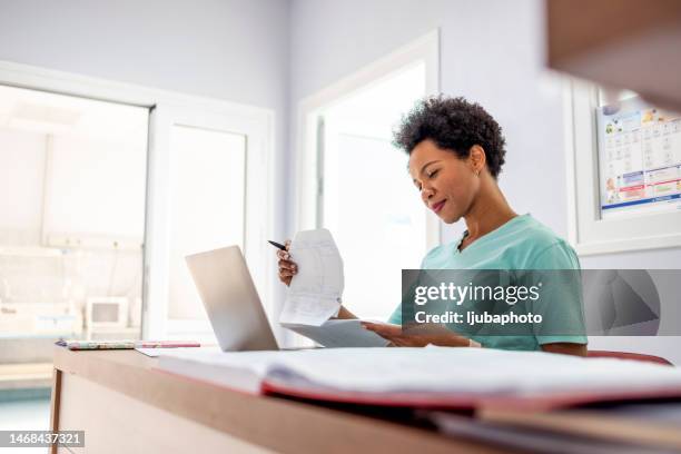 nurse in green medical uniform filing papers - medisch dossier stockfoto's en -beelden