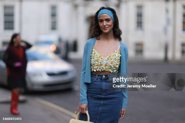 Juny Breeze seen wearing a denim long midi skirt, a cropped sequins flower top, a blue cardigan, a blue hairband, a yellow bag and white heels before...