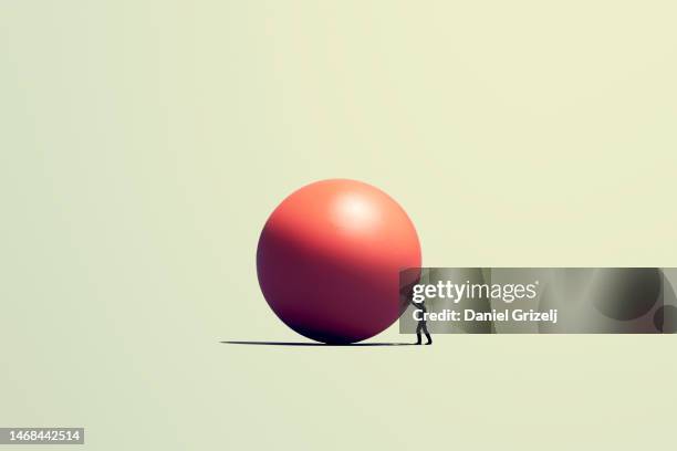 man pushes a huge orb - man with big balls fotografías e imágenes de stock