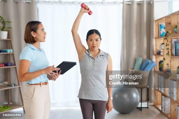 arm physiotherapy, dumbbell and senior asian woman with support help on recovery rehabilitation or motion training. physical therapy portrait, tablet and physiotherapist helping healthcare patient - clinic room stock pictures, royalty-free photos & images