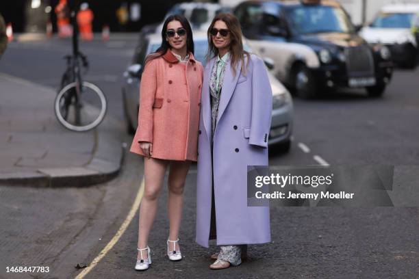 Fashion week guest seen wearing a long purple coat, a matching flower printed suit with a blazer and pants, a blouse and beige ballet flats and...