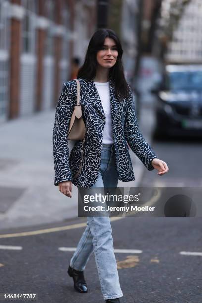 Fashion week guest seen wearing a flower printed blazer, a white shirt, jeans, a beige bag and black boots before the PAUL and JOE show during London...