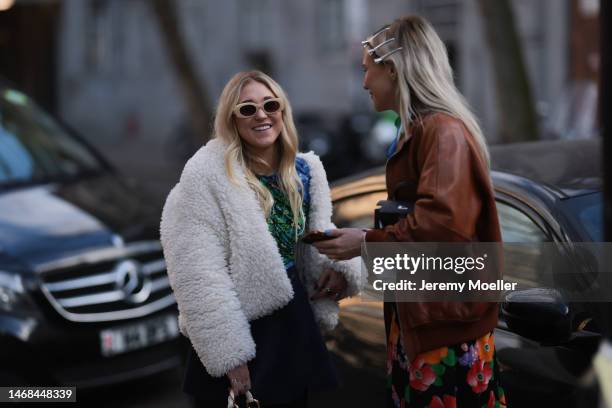 Fashion week guest seen wearing a Hermes mini kelly bag, a brown leather jacket, a colourful flower printed skirt and hairclips and another fashion...