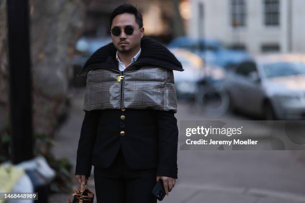 Fashion week guest seen wearing a Louis Vuitton bag, a Fendi checked down cape, dark shades, black pants and a black jacket with a fur collar before...