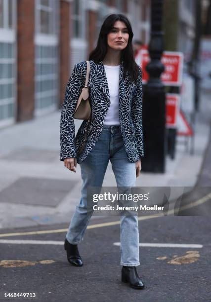 Fashion week guest seen wearing a flower printed blazer, a white shirt, jeans, a beige bag and black boots before the PAUL and JOE show during London...