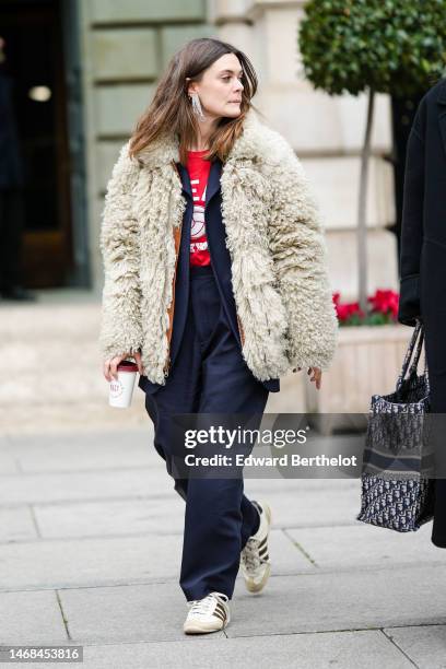 Guest wears a white crystals fringed earrings, a red t-shirt, a black blazer jacket, a white latte sheep oversized coat, black suit pants, white...