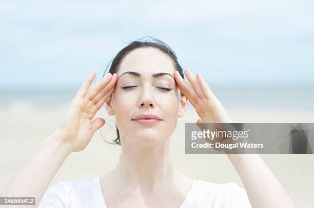 woman at beach with eyes closed and hands on head. - forehead stock-fotos und bilder