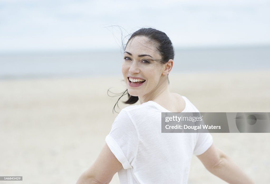 Woman at beach with arms stretched.