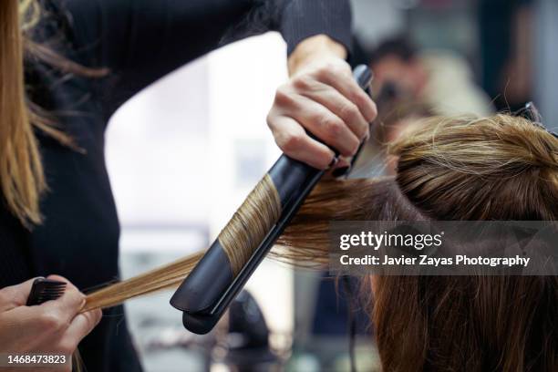 female hairdresser in a hair salon curling a female customer's hair - flat iron stock pictures, royalty-free photos & images