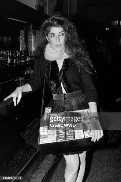 Young woman, dressed as a cigarette girl from the 1950s, holds a tray of cigarette packets at the club Heartbreaker, in New York City