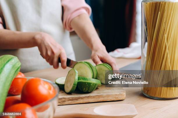 woman cutting fresh green zucchini with knife, cooking food at home healthy eating, fresh vegetables - köchin stock-fotos und bilder