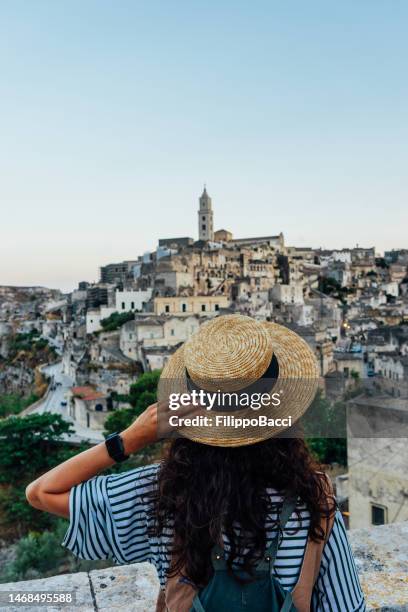 a woman with a straw hat is admiring the beautiful matera ancient city - matera stockfoto's en -beelden