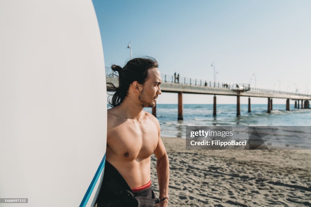 Portrait d’un homme tenant sa planche de surf sur la plage