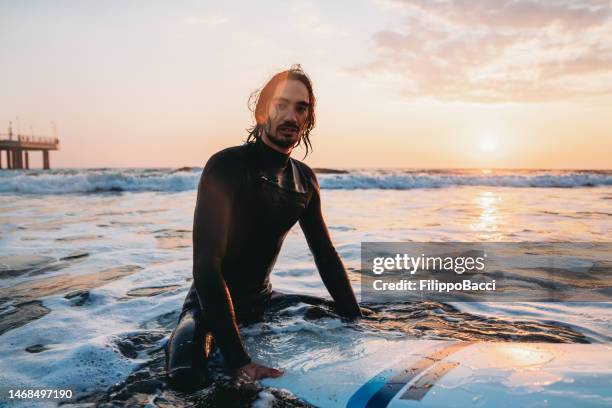 portrait of a man sitting on his surfboard in the sea - beautiful filipina stock pictures, royalty-free photos & images