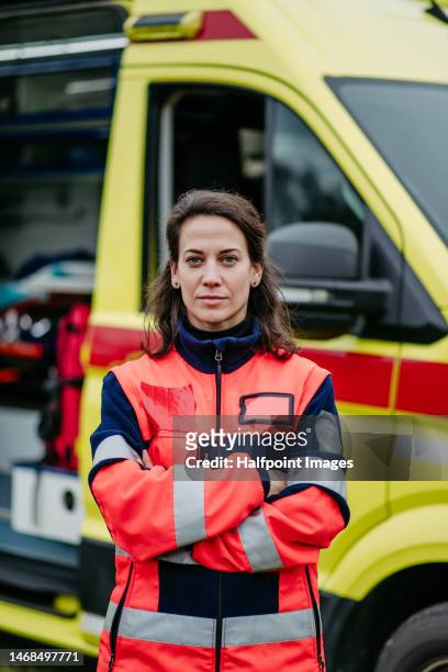 portrait of rescuer woman standing in front of ambulance car. - stretcher stock-fotos und bilder