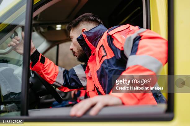 rescuer man getting into the ambulance car. - rotes kreuz stock-fotos und bilder