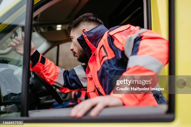 rescuer man getting into the ambulance car. - red cross stock pictures, royalty-free photos & images