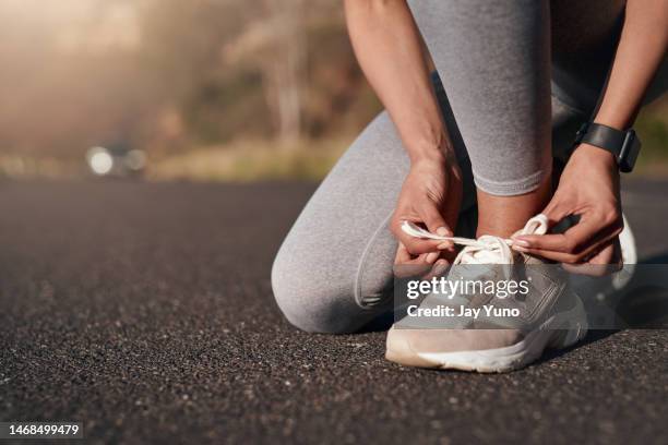 fitness, strada e donna si allacciano le scarpe da ginnastica prima di allenarsi per una maratona, una gara o una competizione. sport, allenamento e atleta donna pronta a iniziare un esercizio cardio all'aperto per la salute in strada - scarpe da ginnastica foto e immagini stock