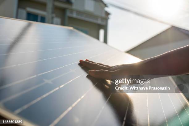 human hand touching solar panel mounted at home - zonnepanelen stockfoto's en -beelden