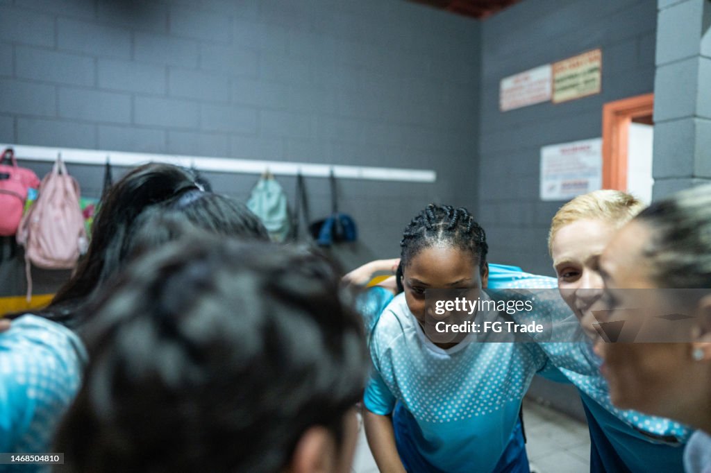 Female soccer team huddling in the locker room
