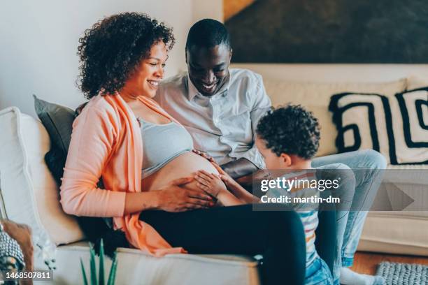 boy with hands on mother’s belly feeling the baby’s movements and kicks - baby kicking stock pictures, royalty-free photos & images