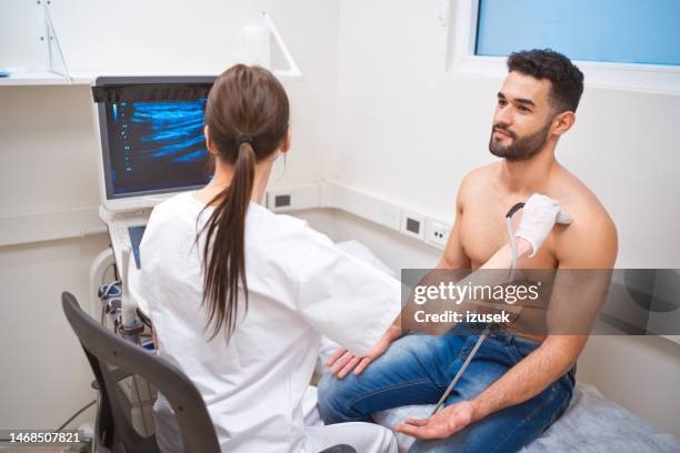 médecin effectuant un test d’écoographie d’un patient torse nu dans la salle d’examen - blouse dexamen médical photos et images de collection