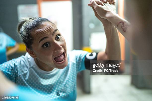 female soccer team captain encouraging colleague before match in the locker room - soccer locker room stock pictures, royalty-free photos & images