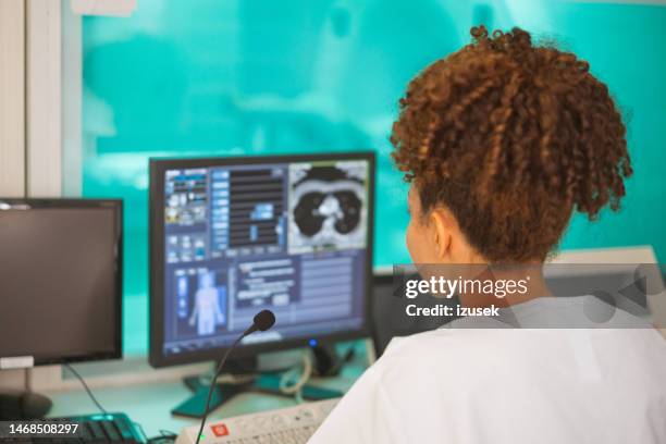 travailleuse de la santé travaillant sur un ordinateur de bureau dans une salle d’examen - blouse dexamen médical photos et images de collection