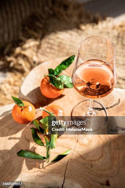 rosé wine glass on mediterranean chair with clementine citrus fruit in sunshine - sunlight through drink glass stock pictures, royalty-free photos & images