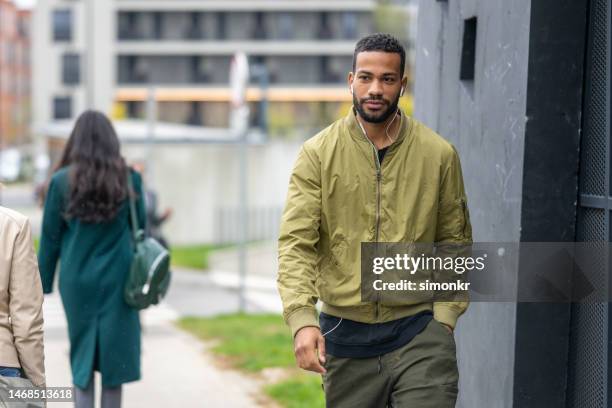 man walking on pavement - green coat stock pictures, royalty-free photos & images