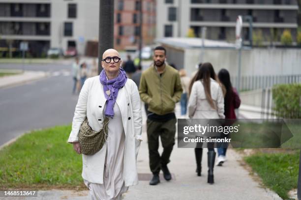 femme marchant sur le trottoir - manteau violet photos et images de collection