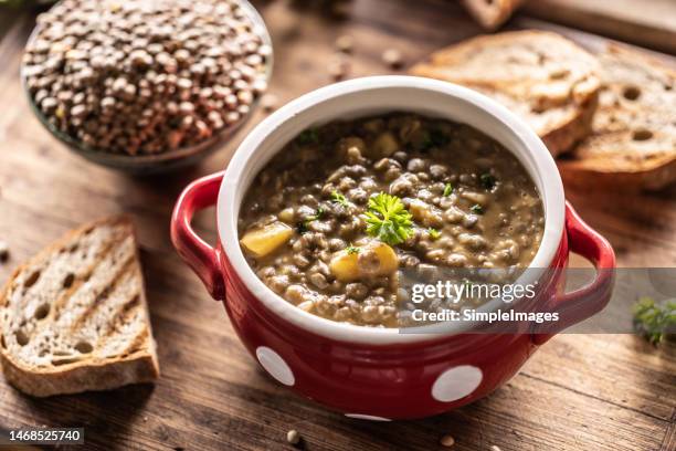 a bowl full of lentil legume soup with baked sausage and fresh bread. - green lentil stock pictures, royalty-free photos & images