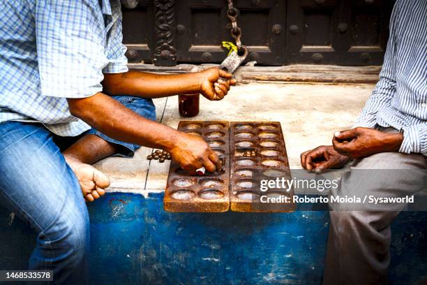 senior men playing bao game on the streets, africa - mancala stockfoto's en -beelden