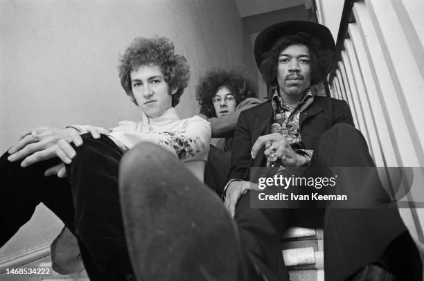 American guitarist and singer Jimi Hendrix seated on right with, on left, drummer Mitch Mitchell and, behind in centre, bassist Noel Redding of the...