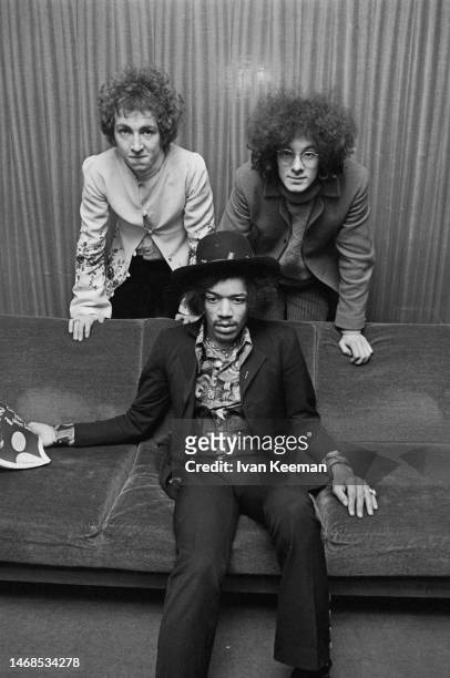 American guitarist and singer Jimi Hendrix seated in centre with, behind on left, drummer Mitch Mitchell and, behind on right, bassist Noel Redding...