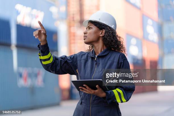 african american dock manager in uniform and safety helmet working and inspector at container cargo with digital tablet. logistics import and export shipping yard. transportation and global business concept - docker stock pictures, royalty-free photos & images