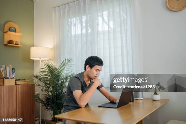 young man with disabilities sits and looks at paper bills in the living room. - different loans stockfoto's en -beelden