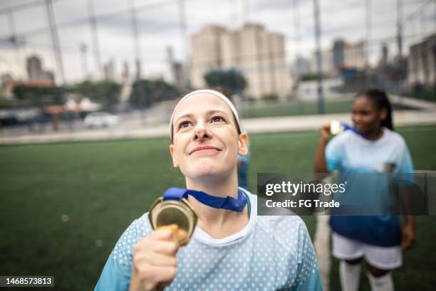 dankbare fußballspielerin mit einer medaille in der hand - medalist stock-fotos und bilder