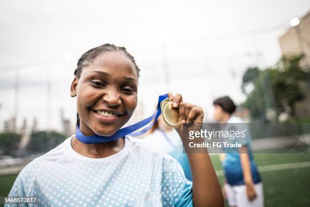 portrait d’une joueuse de soccer célébrant avec une médaille - médaillé photos et images de collection