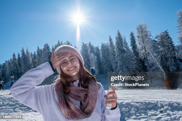 a teenage girl applies sunscreen while skiing. - sun protection stock pictures, royalty-free photos & images