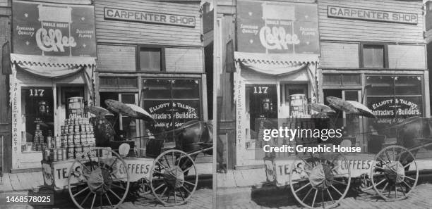Stereoscopic image showing a horse-drawn cart loaded with jars of coffee, parked outside a Tea & Coffee Store, beside a carpenter shop with a sign...