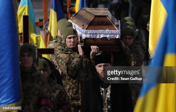 Soldiers carry the coffin of soldier Vladyslav Tkachenko at his funeral and that of a second soldier at the Field of Mars cemetery on February 22,...