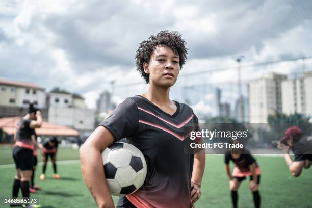 portrait of a female soccer player holding a soccer ball in the field - female football player stock pictures, royalty-free photos & images