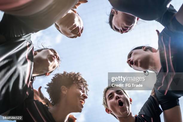 female soccer team huddling in the field - soccer huddle stock pictures, royalty-free photos & images