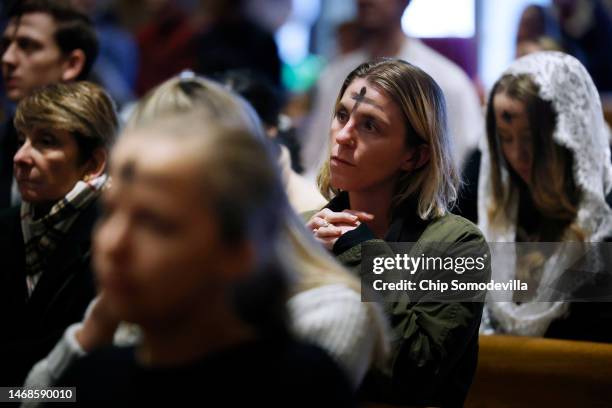 With a cross of ash on her forehead, a woman prays during an Ash Wednesday Mass at the Cathedral of St. Matthew the Apostle on February 22, 2023 in...